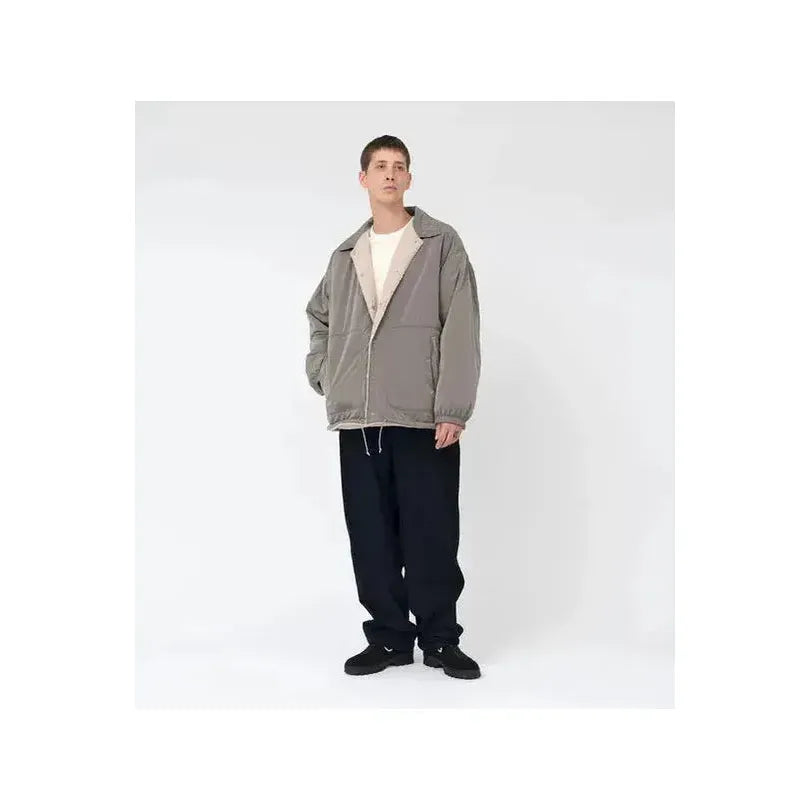 Men's reversible beige wind jacket by nanamica, showing front view with open and closed options, lightweight and windproof.