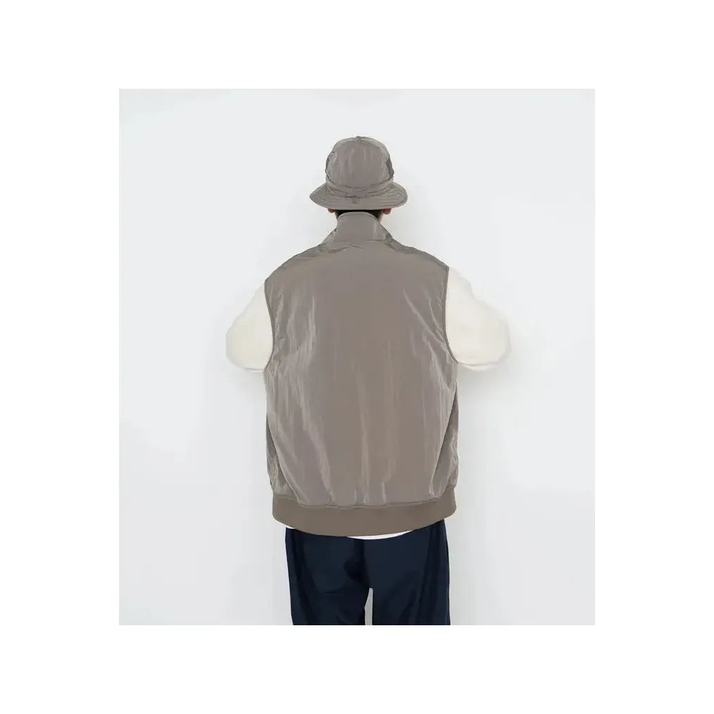 Men's beige zip-up wind vest by nanamica, lightweight and wind-resistant, shown on a plain background.