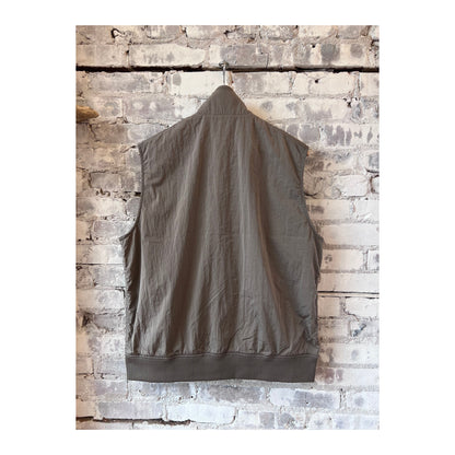 Men's beige nanamica zip-up wind vest, lightweight and weather-resistant, shown on a hanger with a smooth fabric texture.