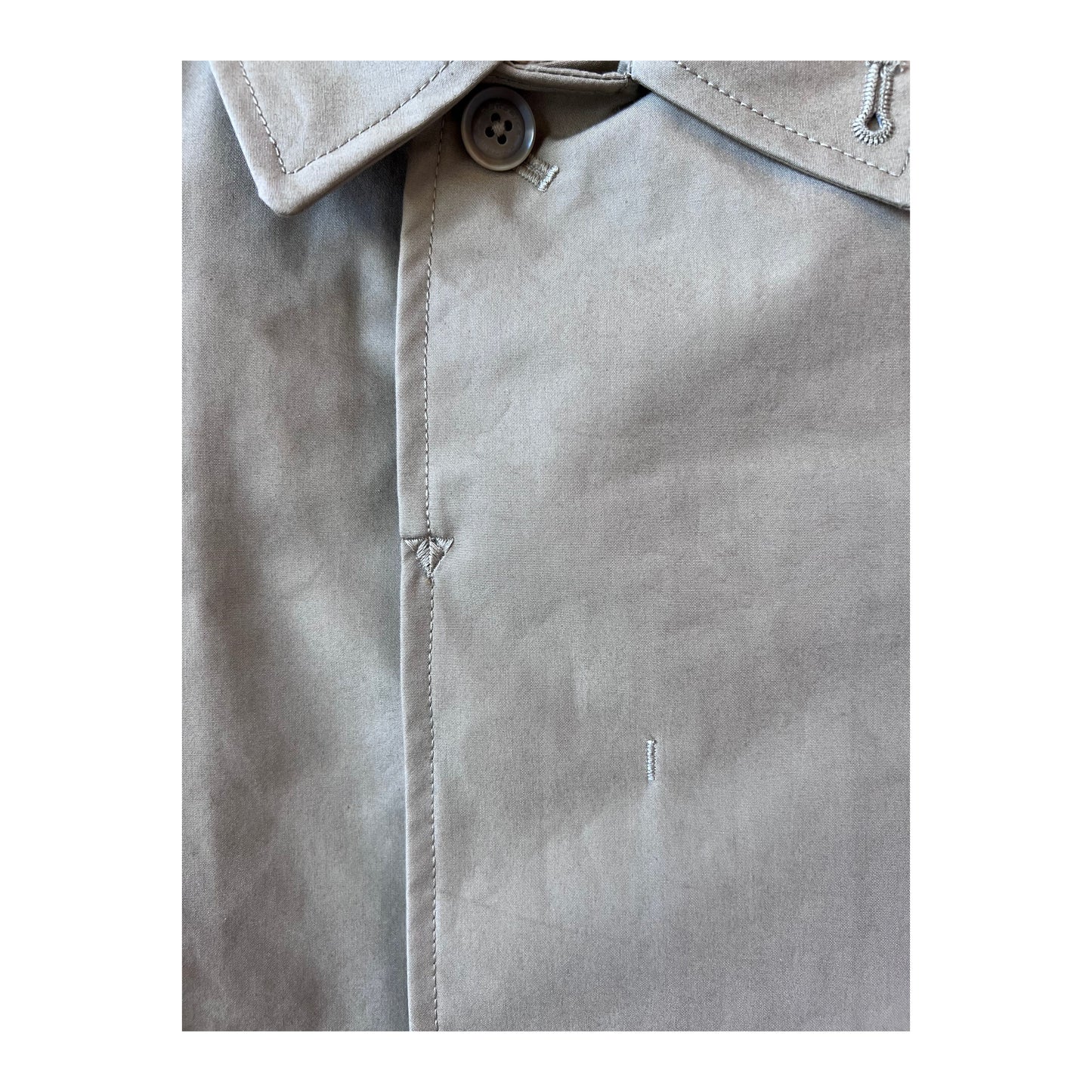 Women's beige nanamica GORE-TEX Soutien Collar Coat hanging on a hanger, showing its tailored collar and waterproof fabric.