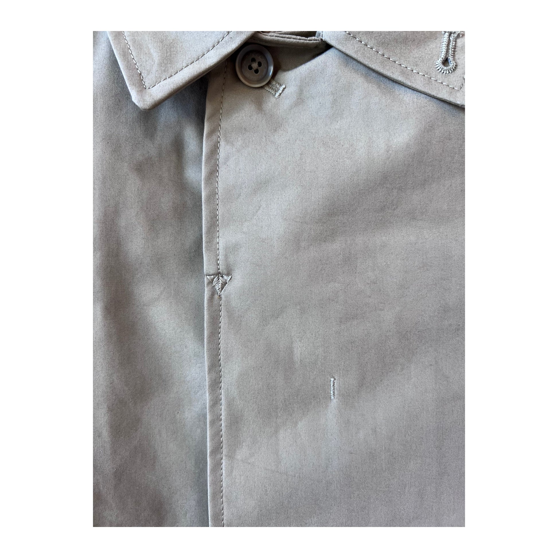 Women's beige nanamica GORE-TEX Soutien Collar Coat hanging on a hanger, showing its tailored collar and waterproof fabric.