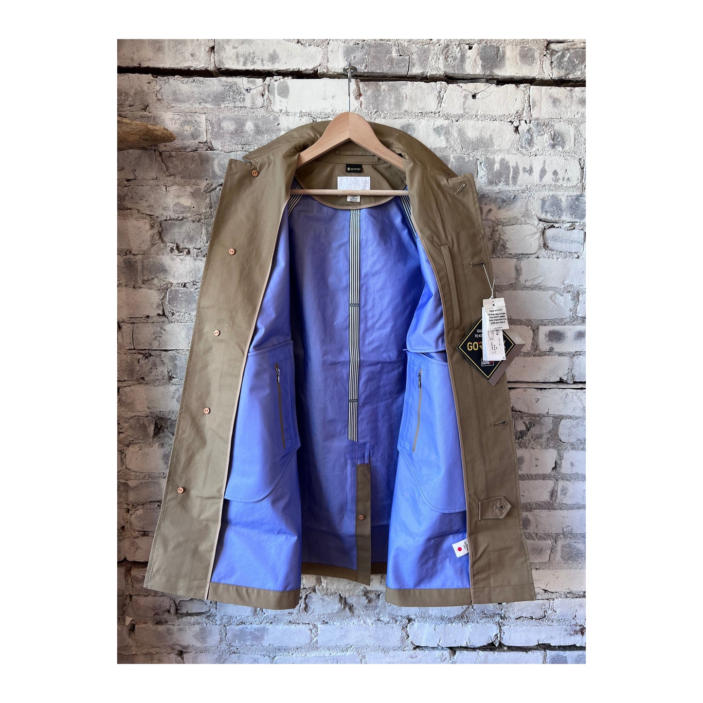 Women's beige nanamica GORE-TEX Soutien Collar Coat with a stylish collar and waterproof fabric, perfect for rainy weather.