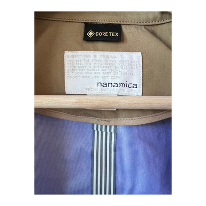 Women's beige GORE-TEX Soutien Collar Coat by nanamica, showcasing the coat's collar, waterproof fabric, and stylish design.