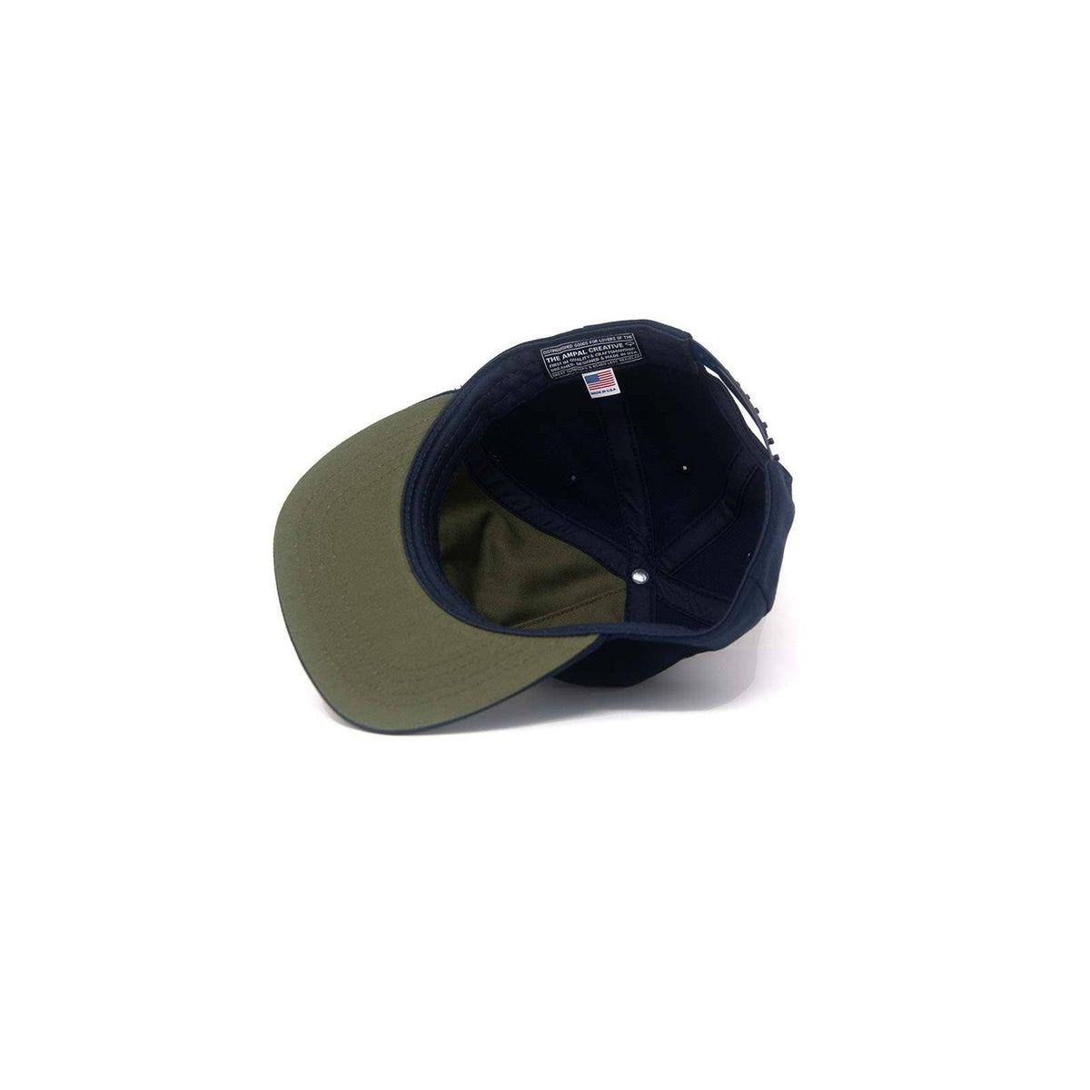 Pacific IV Snapback cap by The Ampal Creative, navy and white with adjustable strap and embroidered logo detail.