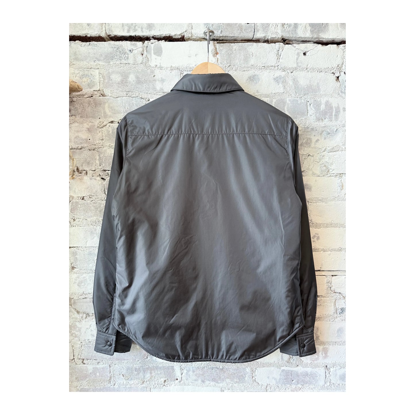 Women's grey padded nylon overshirt by Aspesi, shown in a close-up image highlighting the fabric texture and tailored fit.