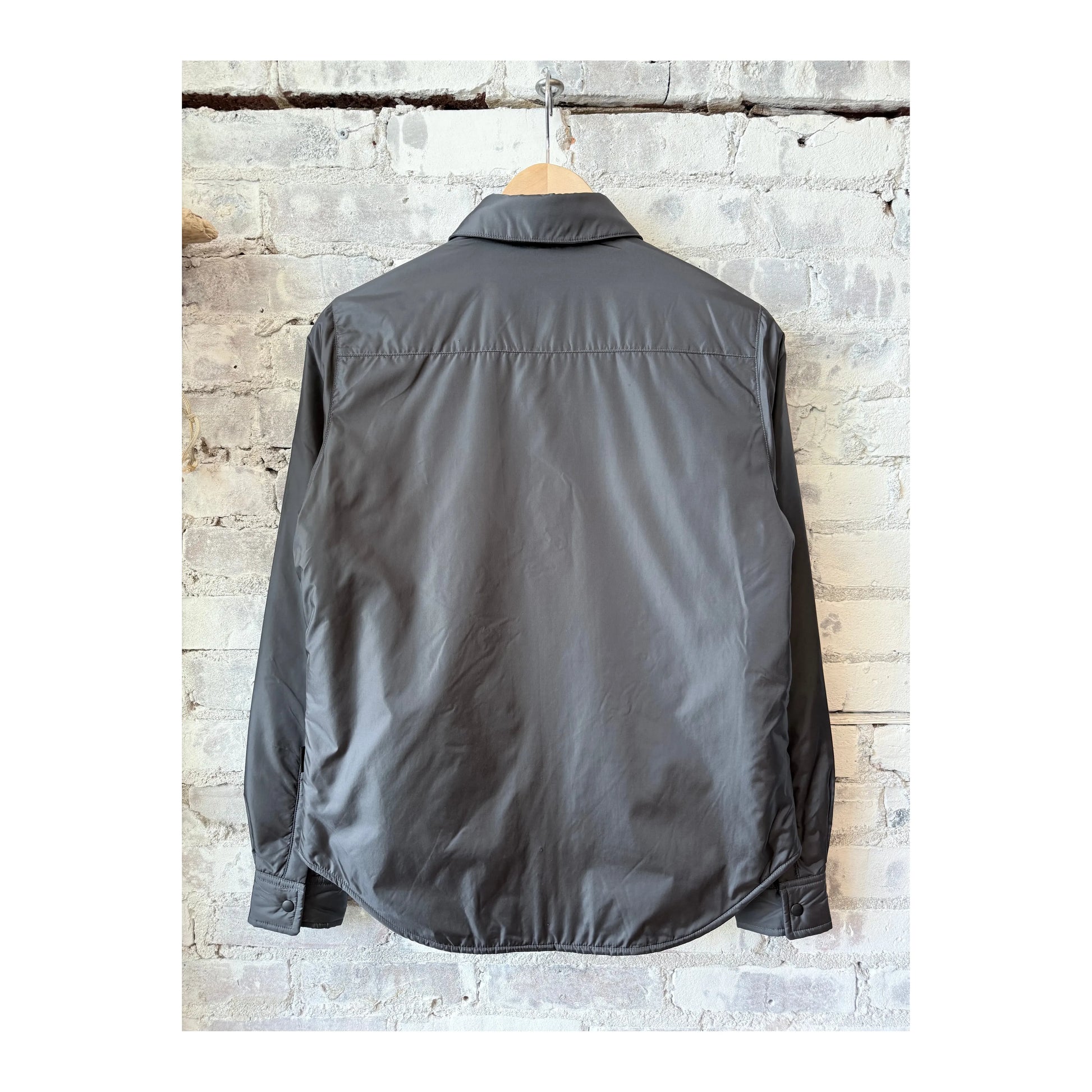 Women's grey padded nylon overshirt by Aspesi, shown in a close-up image highlighting the fabric texture and tailored fit.