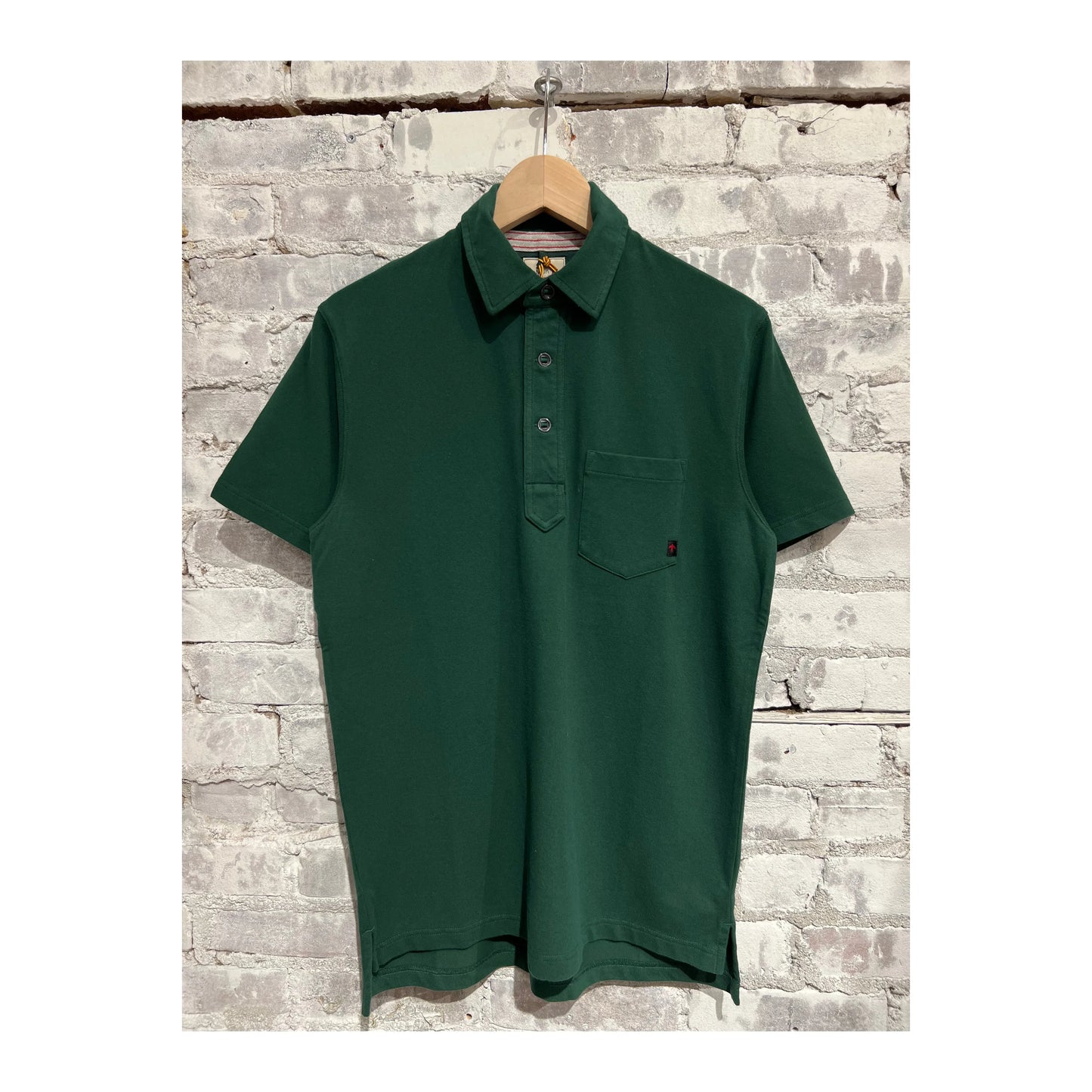 Men's Forest Green Pique Slot Polo shirt by Relwen, showing a close-up of the textured fabric and collar details.