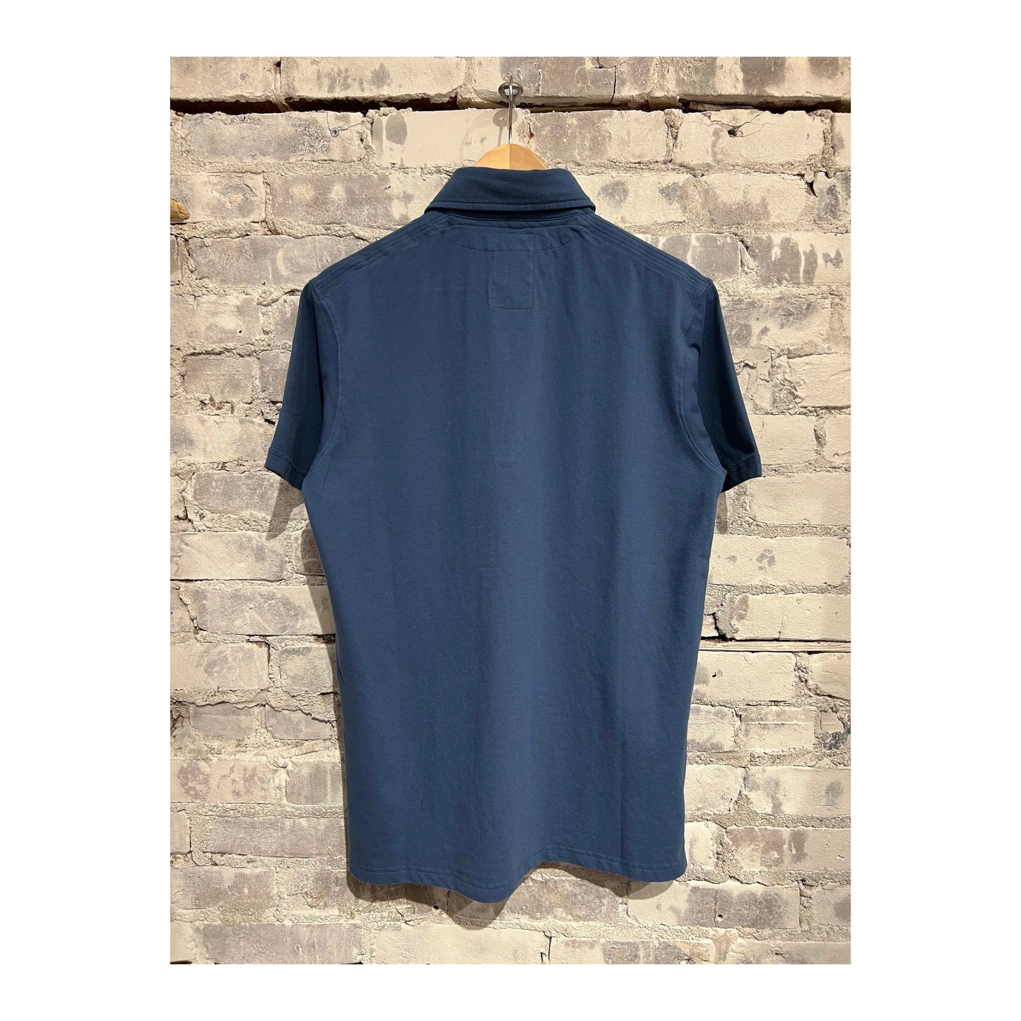 Men's Marine Blue Pique Slot Polo shirt by Relwen, featuring a classic collar and short sleeves, displayed on a hanger.