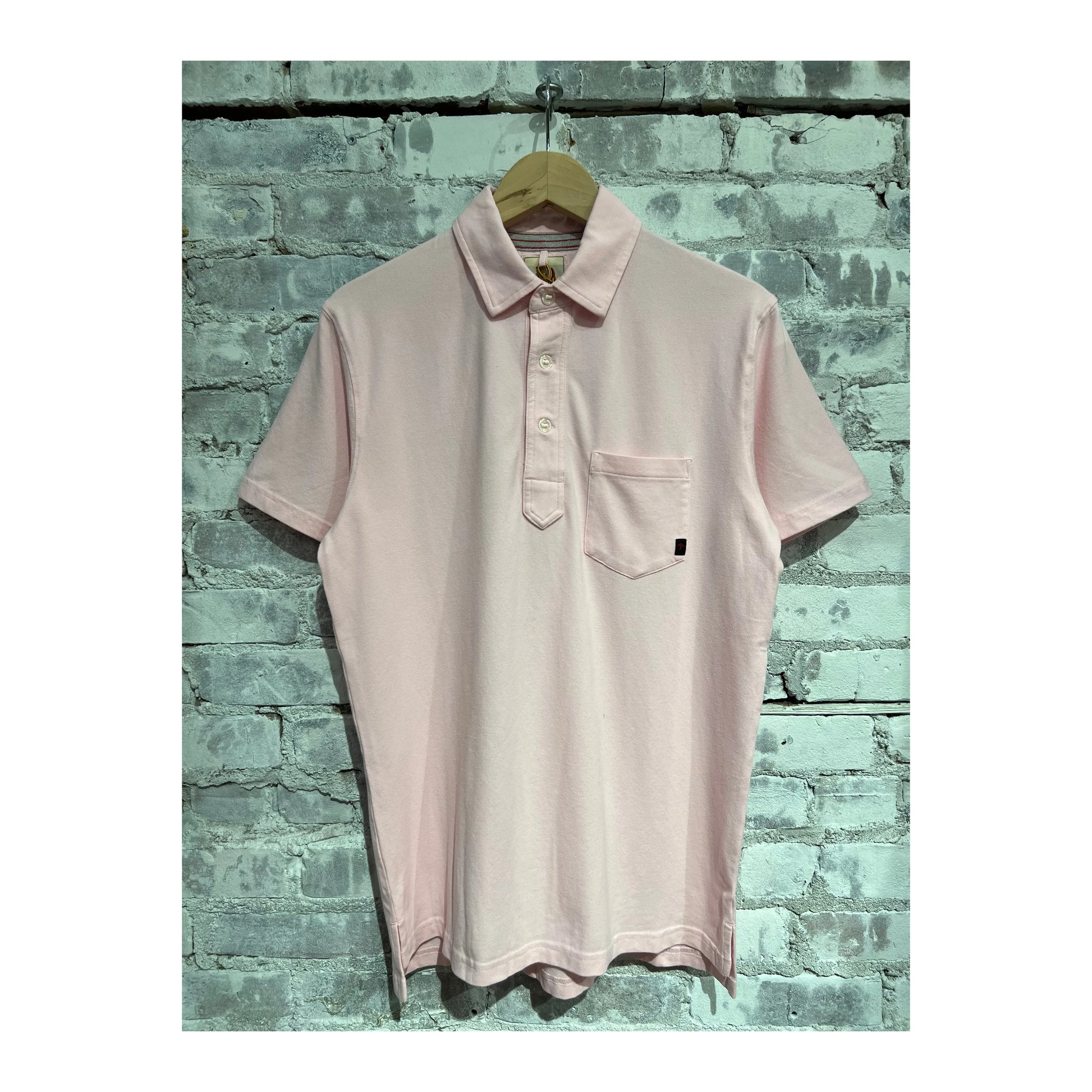 Men's pale pink Pique Slot Polo shirt by Relwen, showing the textured fabric and classic collar detail.