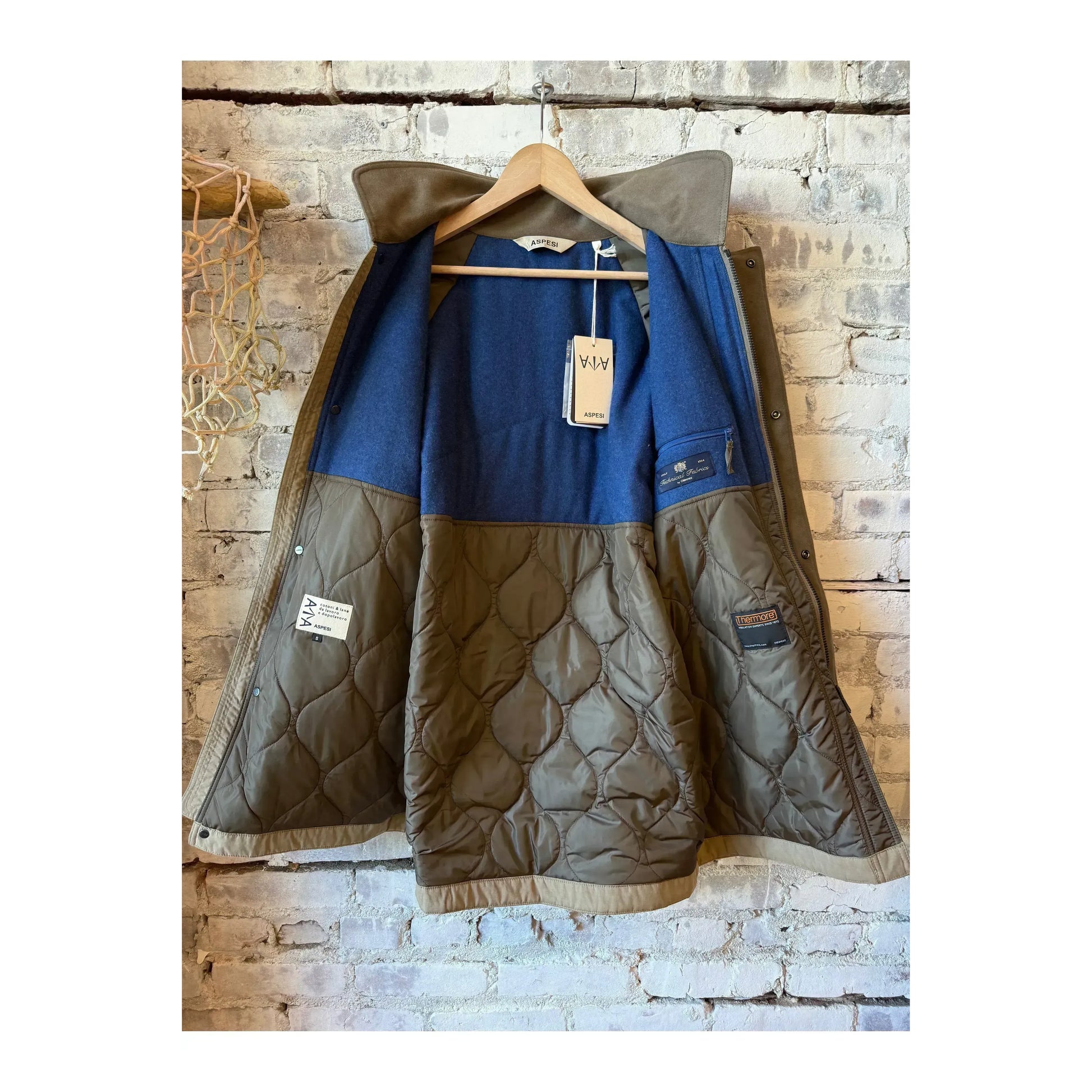 Aspesi men's Schaefer Canvas Car-Coat in dove grey hanging on a clothing rack, showcasing its stylish design and fabric texture.
