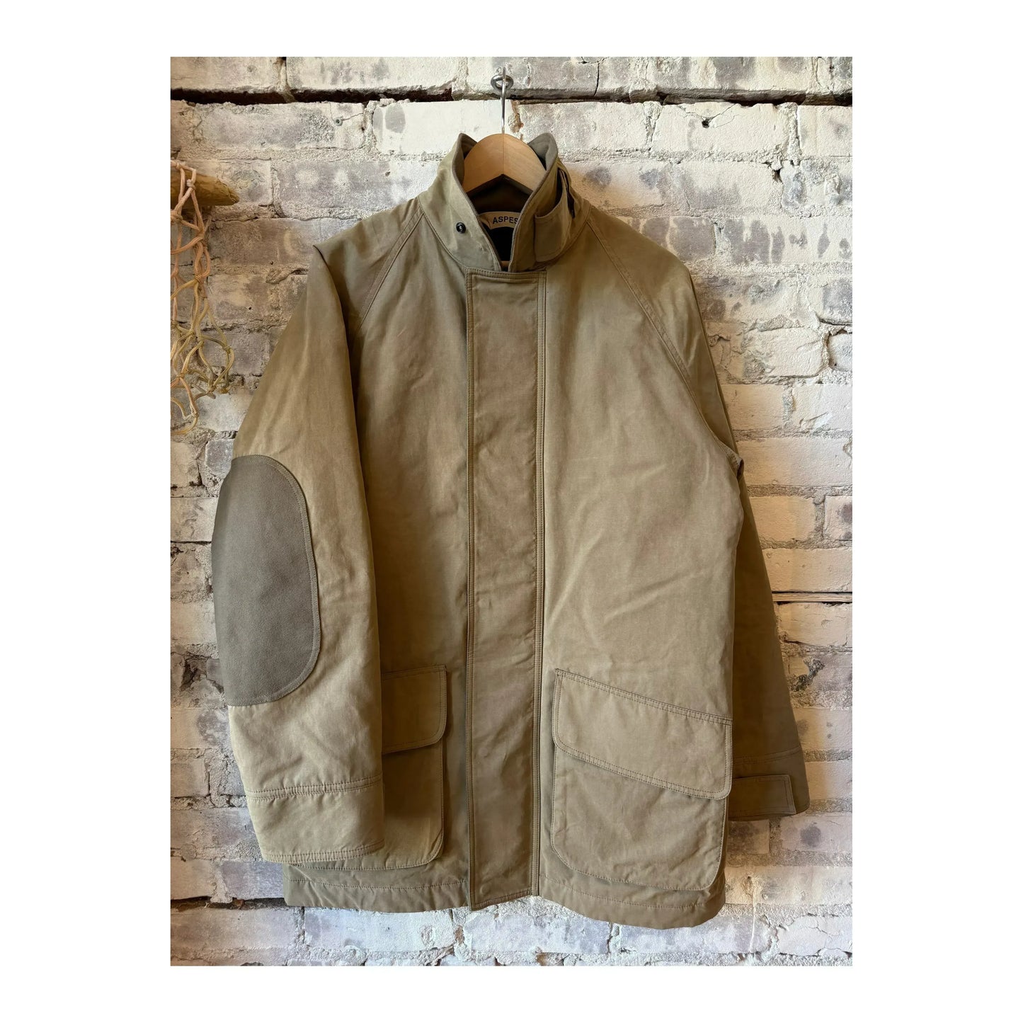 Aspesi men's Schaefer Canvas Car-Coat in dove grey hanging on a clothing rack.