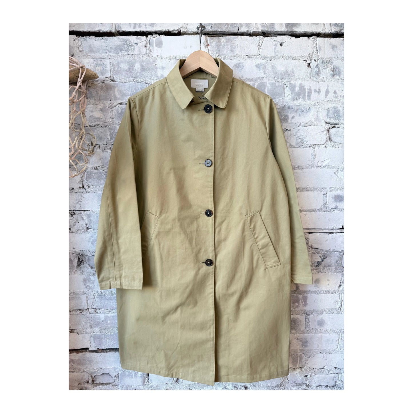 Women's Sylvie MacKintosh trench coat in tan by M.Patmos, shown on a hanger with a classic double-breasted design and belt.