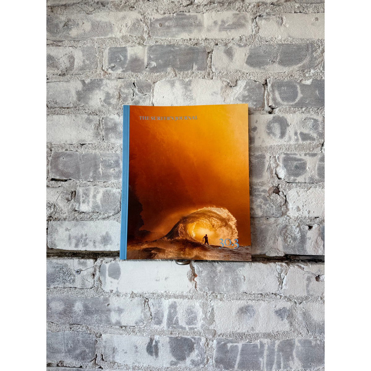 Stack of The Surfer's Journal 30 editions, featuring vintage-style covers and surf-inspired artwork on a wooden surface.