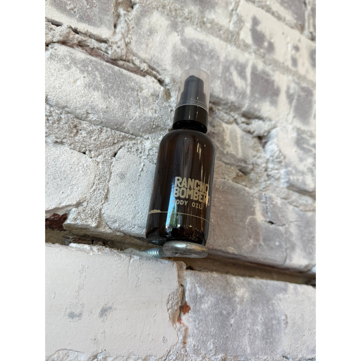 Rancho Bombero Total Body Oil 2 oz. in a clear glass bottle with a pump dispenser, accessory for skincare and massage.
