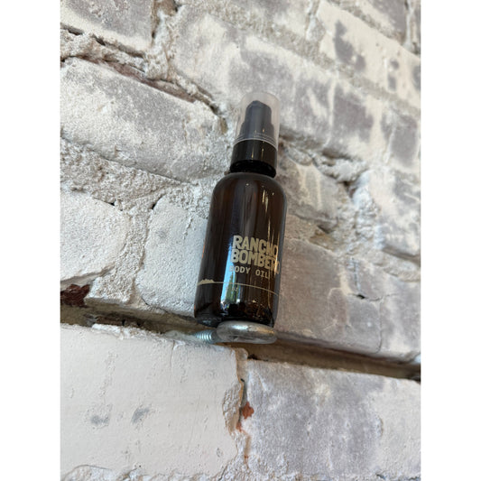 Rancho Bombero Total Body Oil 2 oz. in a clear glass bottle with a pump dispenser, designed for nourishing skin.
