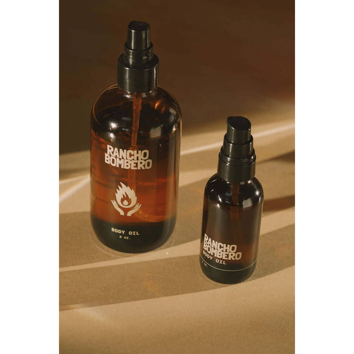 Rancho Bombero Total Body Oil in a 2 oz. bottle, designed as a skincare accessory, with a sleek, transparent container and pump lid.