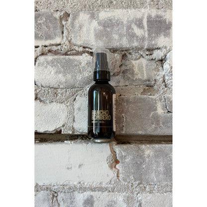 Rancho Bombero total body oil 2 oz. in a clear glass bottle with a pump dispenser, designed for skincare and body nourishment.