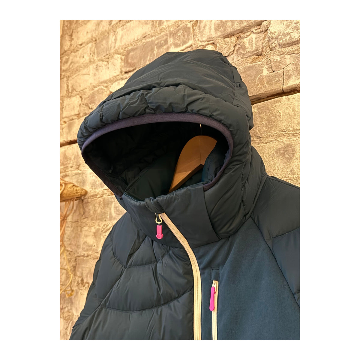 Women's Wildpuff Packable Removable Hood Jacket by Seniq in Slushi color, shown folded and partially unzipped with hood attached.