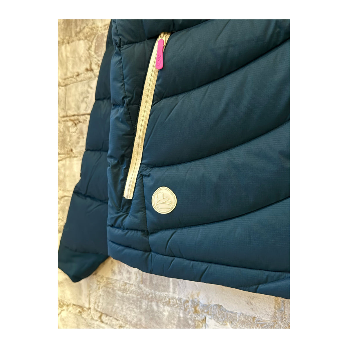 Women's Wildpuff Packable Removable Hood Jacket by Seniq in Slushi color, shown folded with the hood visible and lightweight design.
