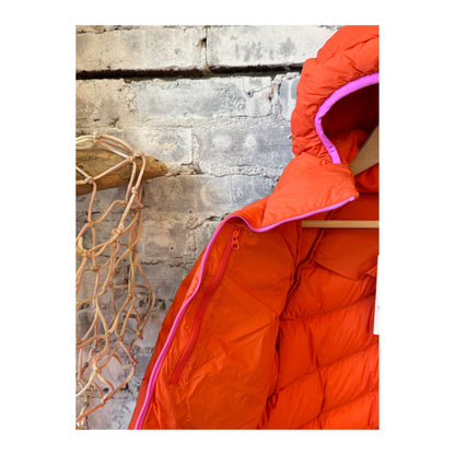 Women's Wildpuff Packable Removable Hood Jacket by Seniq in spicy color, shown with the hood removed and packed in a compact form.