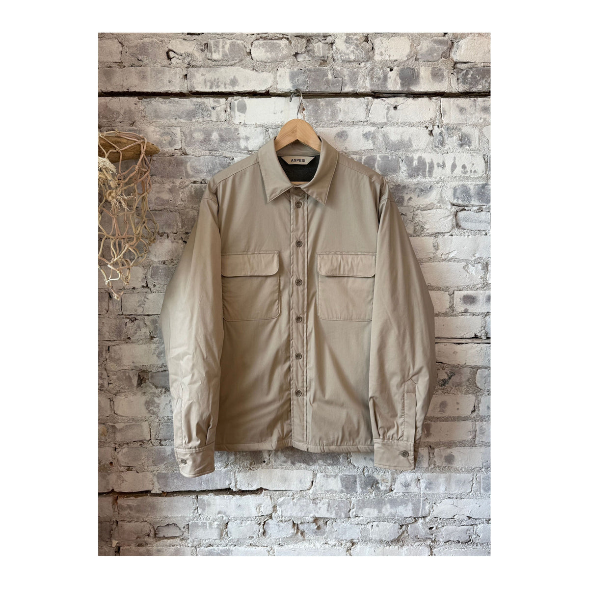 Men's Aspesi Yoshitaka cotton nylon shirt jacket in colonial beige, shown hanging with front view and button details.