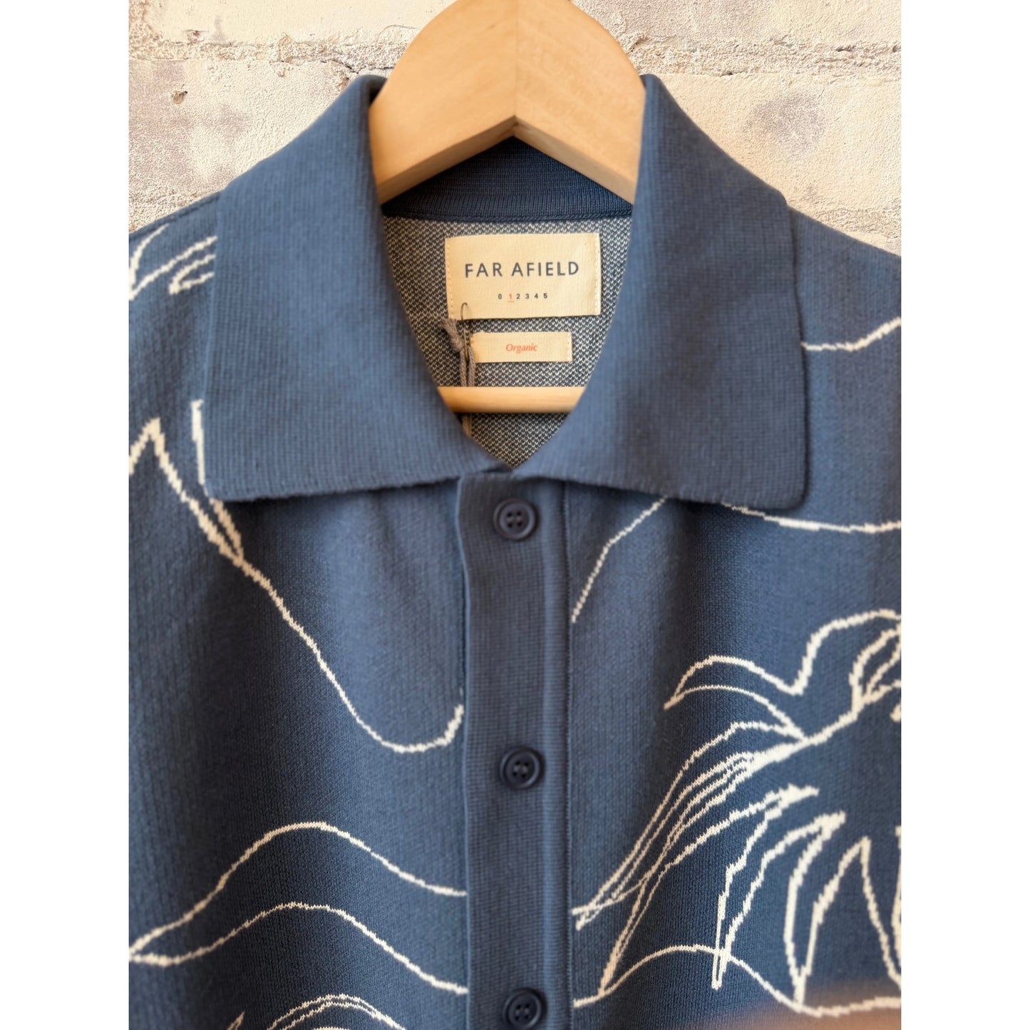 Men's Zig knitted shirt in faded navy with white palm patterns, made by Far Afield, featuring a close-up of the textured fabric.
